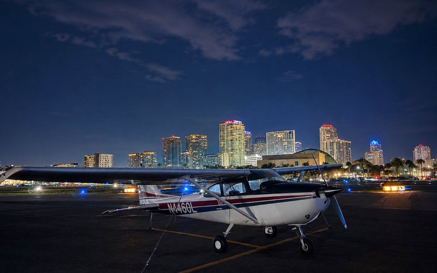 The Cessna 172 on the ramp at night with the downtown St. Petersburg skyline lit up behind it
